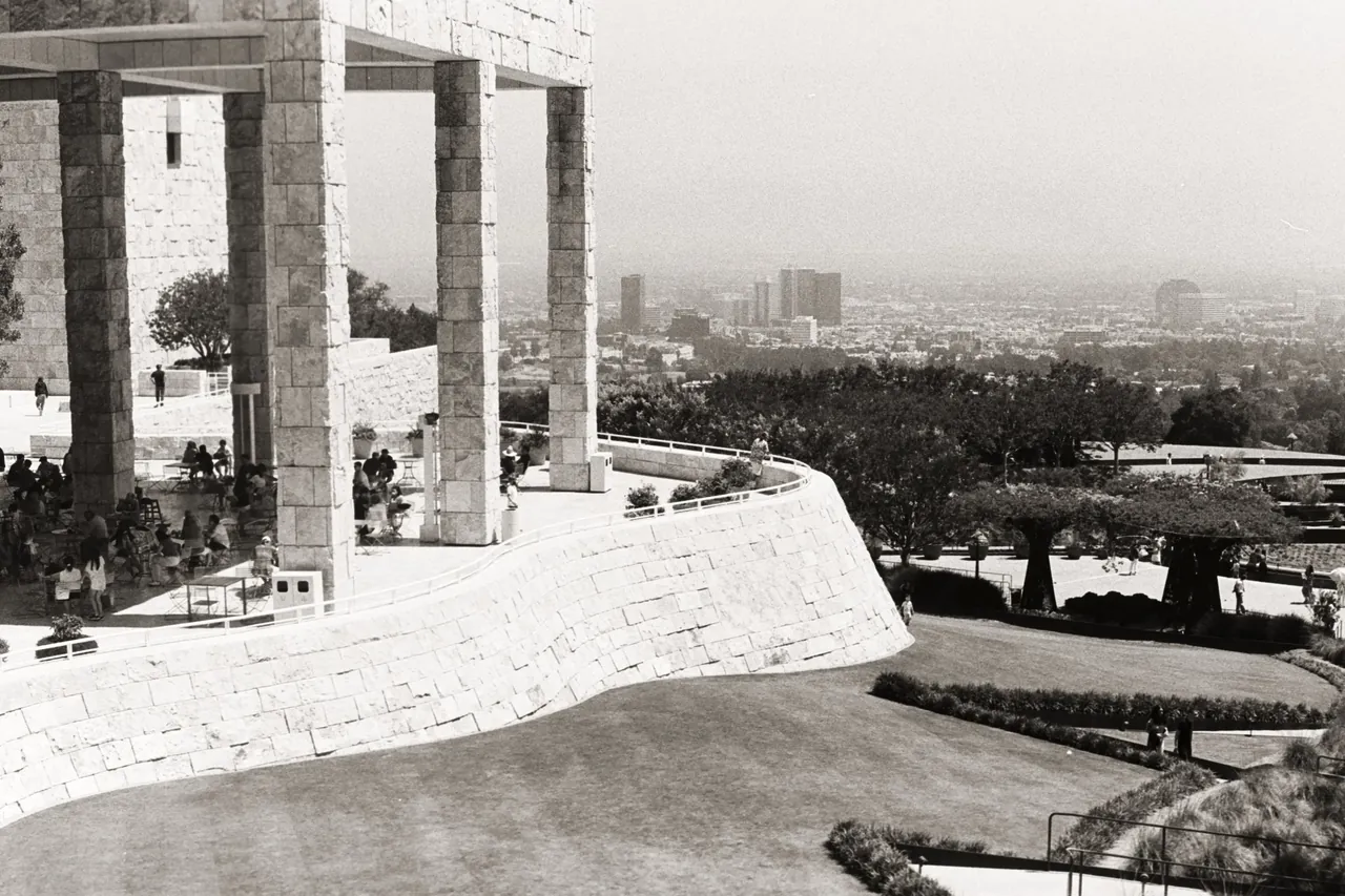 Black-and-white photo of the Getty Center’s stone colonnade overlooking a terrace of cafe tables with the Los Angeles skyline in the distance