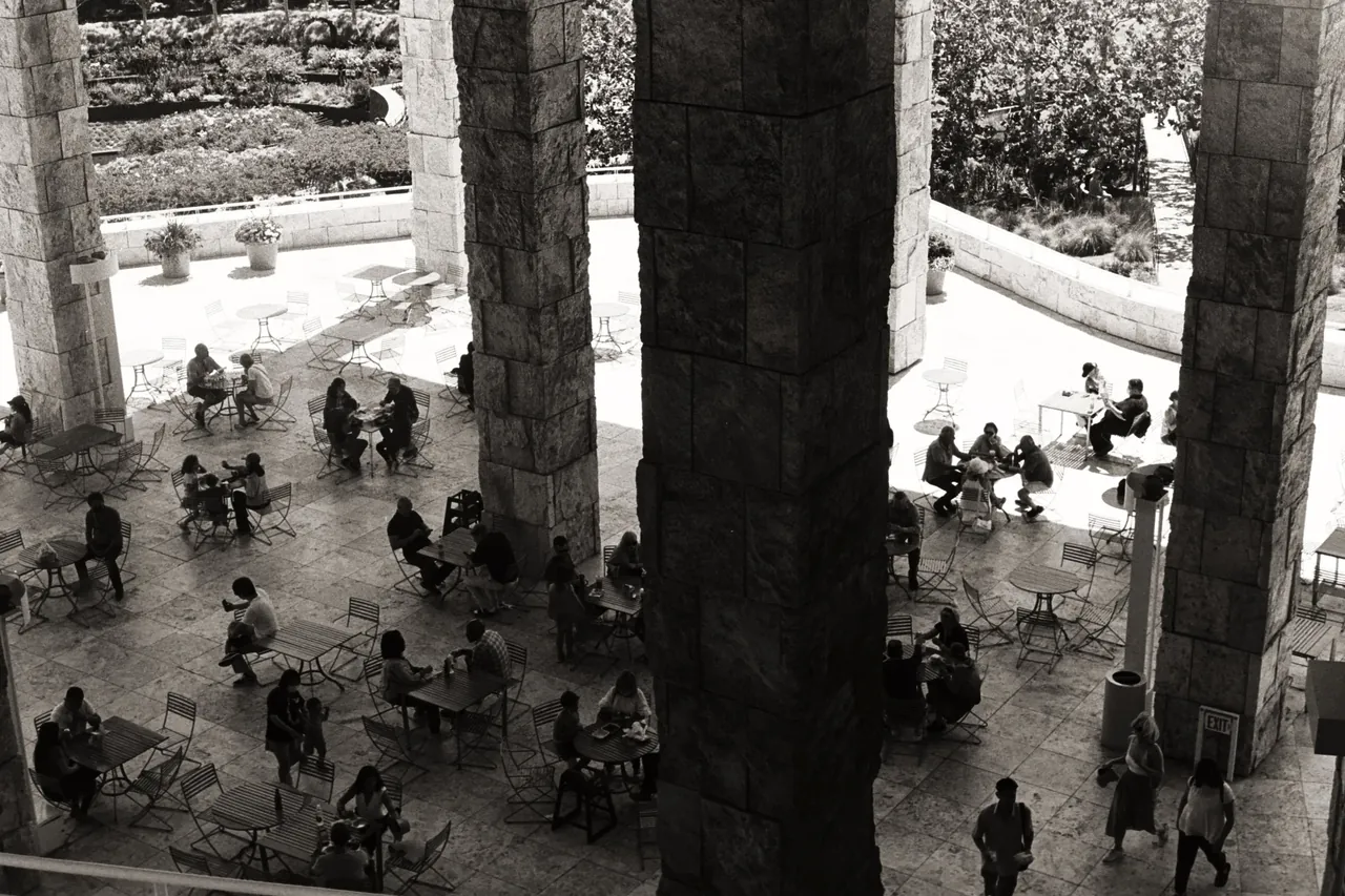Black-and-white aerial view of the Getty Center’s stone columns above a courtyard filled with cafe tables and visitors
