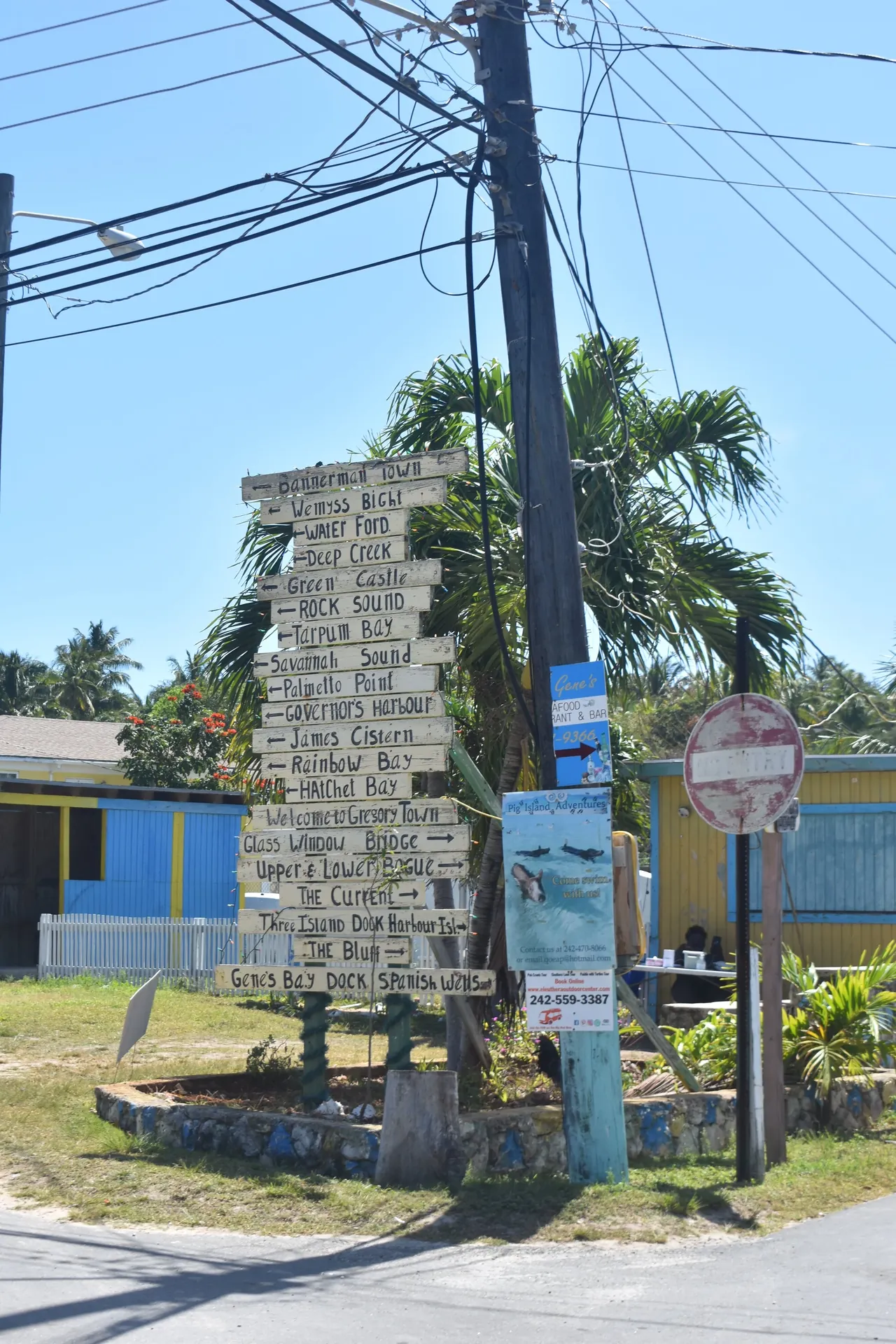 A wooden signpost stacked with hand-painted directions to towns across Eleuthera, Bahamas